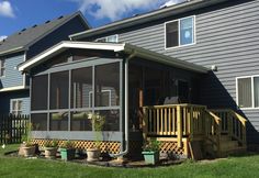 a house with a screened porch in front of it and potted plants on the side