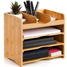 a wooden desk organizer with three compartments and pen holders on top of each shelf, holding various office supplies