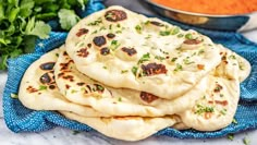 several pita breads stacked on top of each other with sauce in the background