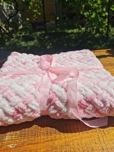 a pink and white blanket on top of a wooden table