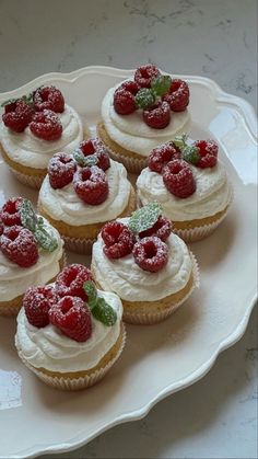 small cupcakes with white frosting and raspberries on top