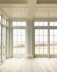 an empty room with lots of windows and wood flooring on the side of it