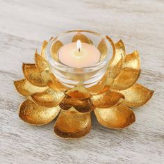 a candle that is sitting in a glass bowl on a wooden table with leaves around it