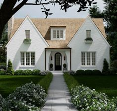 a large white house with lots of windows and plants around it's front door