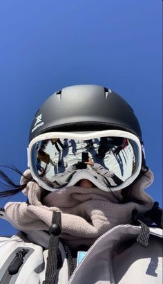 a person wearing ski goggles and a black helmet is standing in front of a blue sky