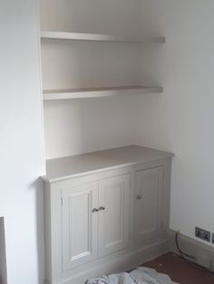 an empty room with some white shelves and cupboards on the wall next to it