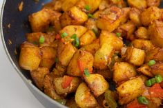 a pan filled with fried food on top of a white countertop next to a wooden spoon