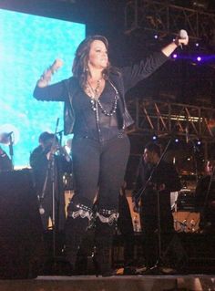 a woman standing on top of a stage with her arms out in front of the crowd