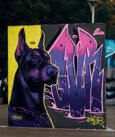 a large black dog standing next to a wall covered in graffiti