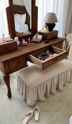 a bedroom with a vanity, mirror and footstool on the floor in front of it