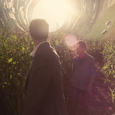 two men are standing in the middle of a corn field looking at something that looks like a spaceship