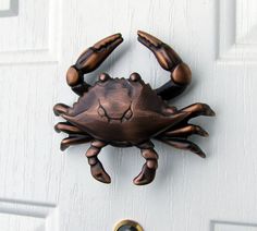 a metal crab door knocker on a white door