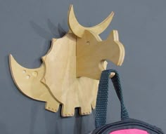 a wooden rhinoceros head hanging on the wall next to a pink and blue purse