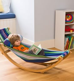 a little boy laying in a hammock reading a book