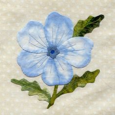 a blue flower with green leaves on a white polka dot fabric background, in the middle of an embroidered design