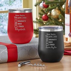 two wine glasses sitting next to each other on top of a table near a christmas tree