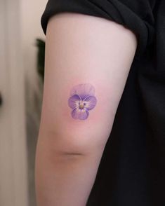 a woman's arm with a purple flower tattoo on it