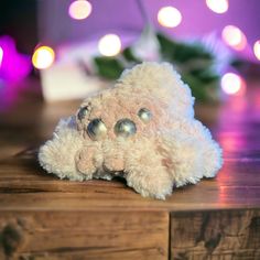 a white teddy bear laying on top of a wooden table with lights in the background