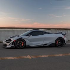 a white sports car parked on the side of the road next to a concrete wall