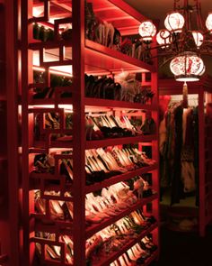 the closet is full of clothes and other items for sale on shelves in red lighting