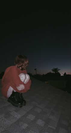 a person sitting on the ground with their arms around each other and looking at something in the sky