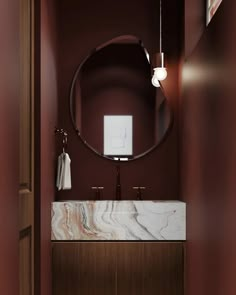 a bathroom with a round mirror and marble sink in the center, along with dark red walls