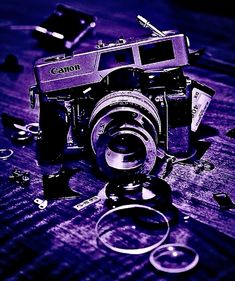 an old camera sitting on top of a wooden table next to some broken up objects