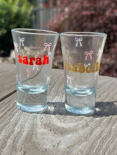 two shot glasses sitting on top of a wooden table next to each other with the word saraba written on them