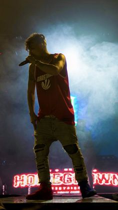 a man standing on top of a stage with his hand in his mouth and lights behind him