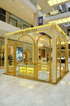 the interior of an upscale shopping mall with gold and white accents, including chandeliers