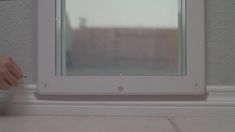 a person holding a pen in front of a window with the reflection of a building on it