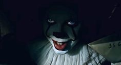 a creepy clown with big blue eyes and white hair is standing in front of a dark background