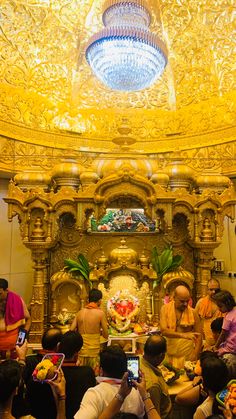 a group of people taking pictures in front of a golden altar with buddha statues on it