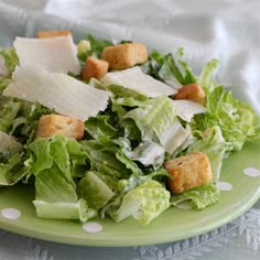 a green plate topped with lettuce and croutons