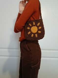 a woman is standing with her hand on her hip wearing a crocheted bag