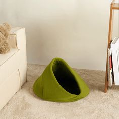 a dog laying on the floor next to a green cone shaped bed in a living room