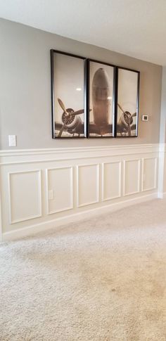 two framed pictures hang on the wall in an empty room with carpeted flooring