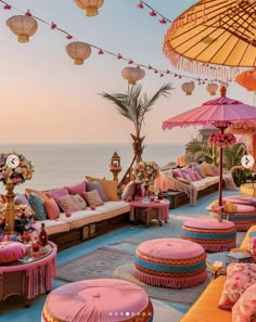 an outdoor seating area with umbrellas and flowers on the ground next to the ocean