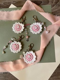 some pink and white crocheted flowers are on a piece of fabric next to scissors