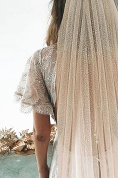 the back of a woman's wedding dress, with her veil draped over her shoulder