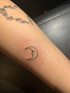 a woman's arm with a tattoo that has a crescent moon and flowers on it