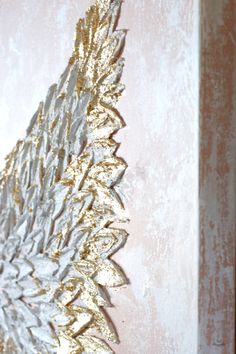 a gold and silver leaf on a pink wall