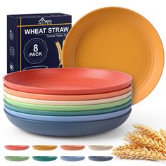 a stack of colorful plates next to a box of wheat straw