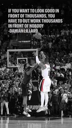 two basketball players jumping up to dunk the ball in front of a large crowd