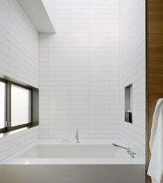 a bathroom with a white bathtub next to a window and towel on the wall