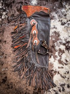 a leather purse with fringes and scissors on top of a cowhide area rug