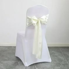 a white chair with a bow tied to it's back sitting on a tile floor