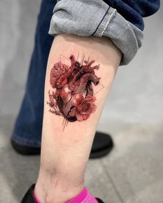 a person with a heart tattoo on their leg and the legs are covered in flowers