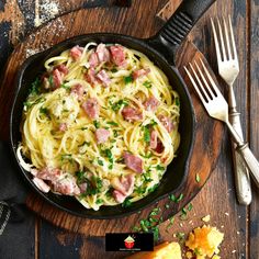 pasta with ham and parsley in a cast iron skillet on a wooden table