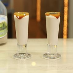 two shot glasses filled with liquid sitting on top of a counter